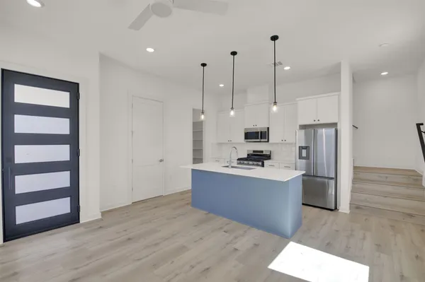 a kitchen with stainless steel appliances kitchen island a refrigerator sink and cabinets