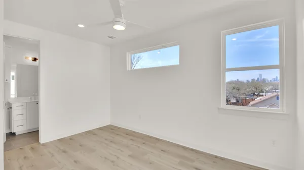a view of an empty room with wooden floor and a bathroom