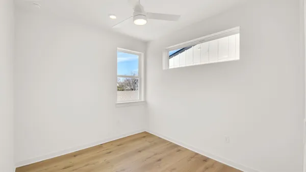 an empty room with wooden floor and windows