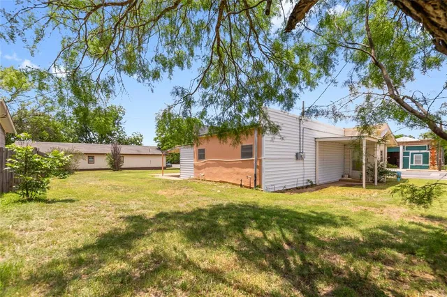 a view of a house with a yard and a large tree