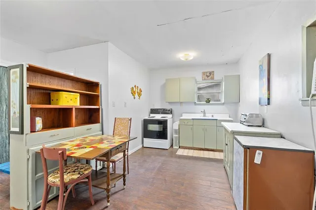 a kitchen with stainless steel appliances granite countertop a stove top oven a sink dishwasher and white cabinets with wooden floor