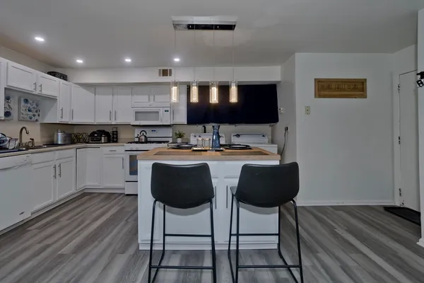 a kitchen with kitchen island granite countertop a sink cabinets and wooden floor