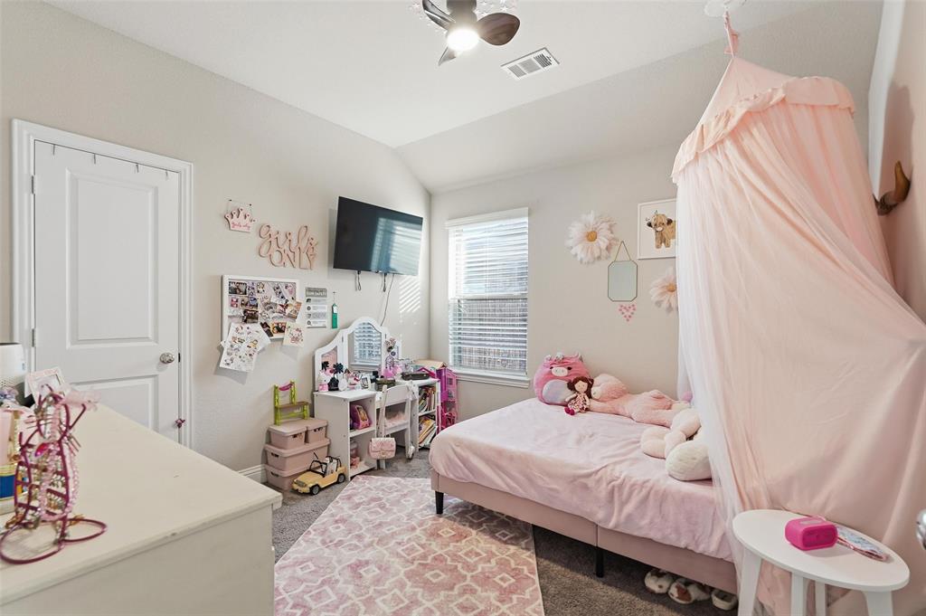 2148 Erika Lane Forney, TX 75126 - Photo 13 of 21 a bedroom with a bed and a flat tv screen on the dresser
