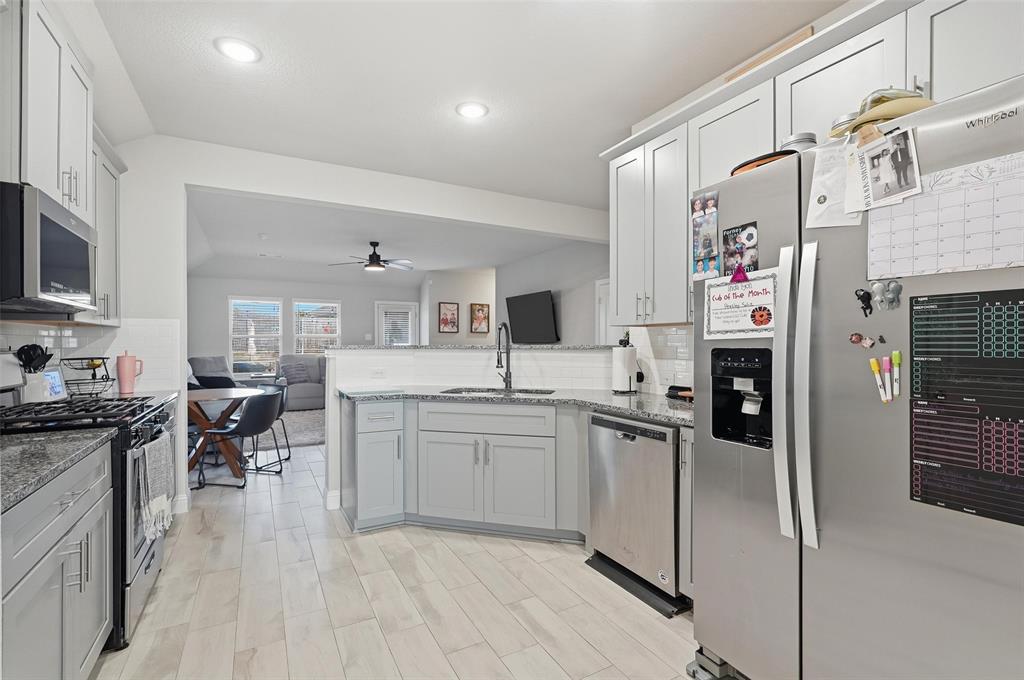 2148 Erika Lane Forney, TX 75126 - Photo 2 of 21 a kitchen with stainless steel appliances granite countertop a refrigerator a sink dishwasher and white cabinets with wooden floor