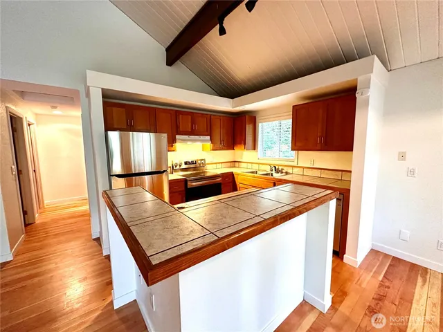 a kitchen with stainless steel appliances granite countertop a sink a stove and a refrigerator