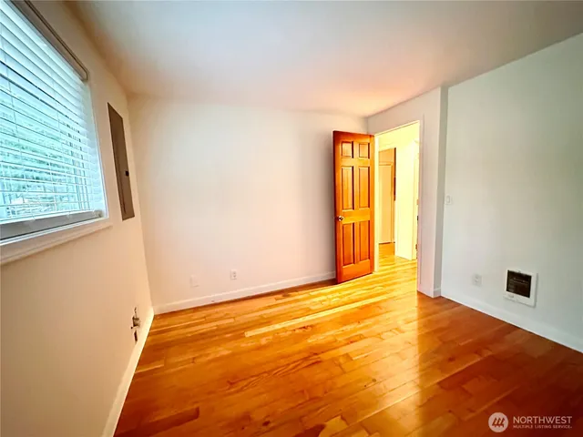 a view of an empty room with wooden floor and a window