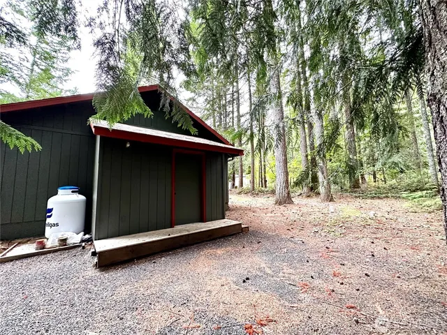 a backyard of a house with a large tree and wooden fence