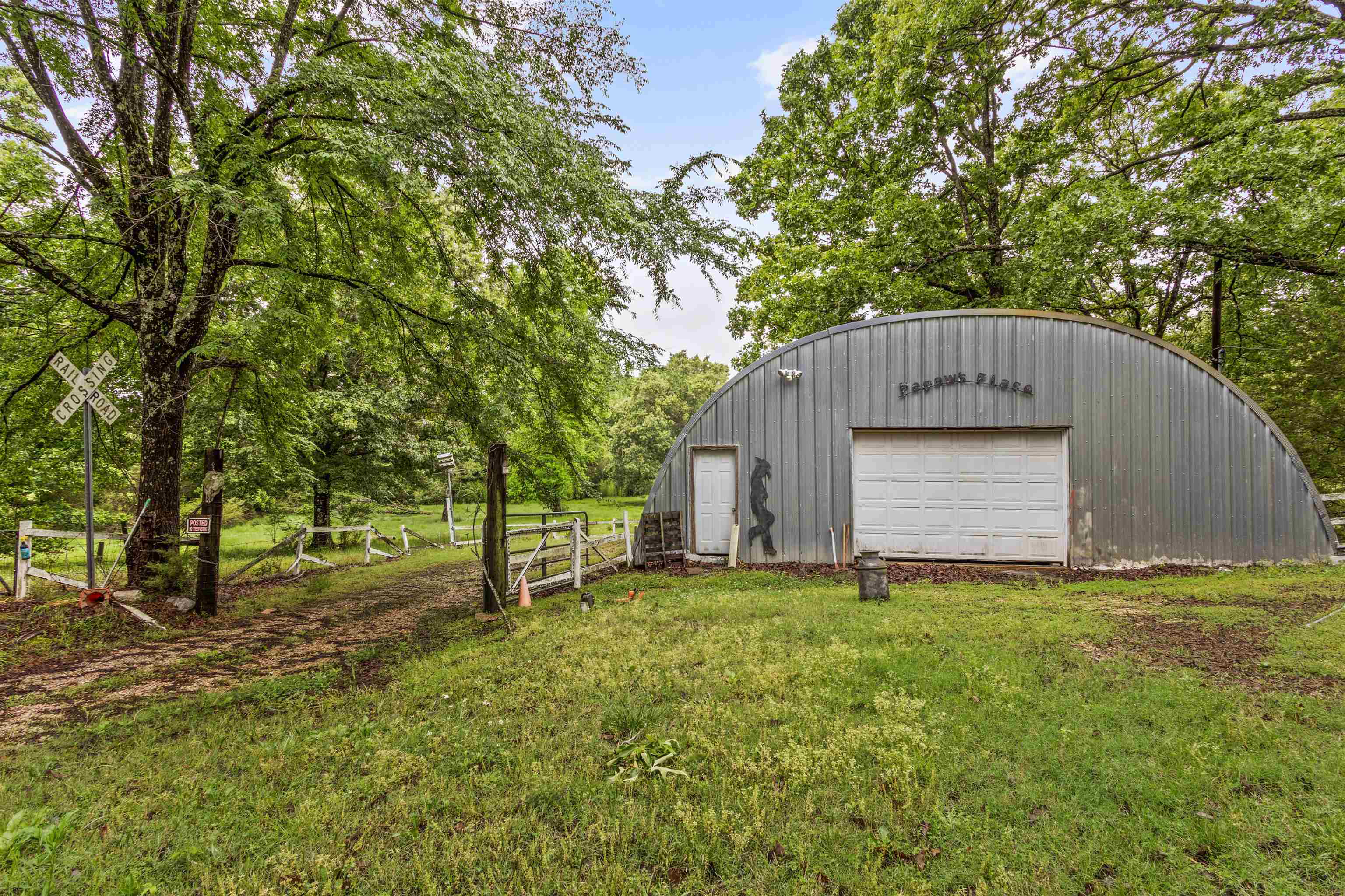 1147 North Collierville Arlington Road Collierville, TN 38017 - Photo 10 of 17 Quonset hut structure with a corrugated metal exterior, featuring a white overhead garage door and a separate entry door