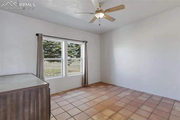 an empty room with chandelier fan and window