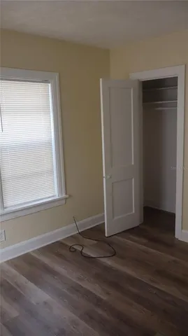 an empty room with wooden floor and window