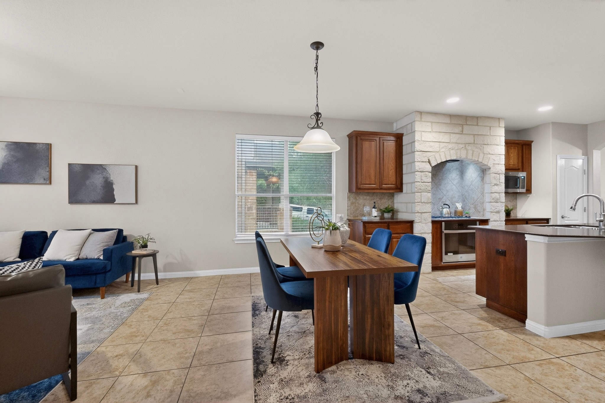 178 Limestone Trail Austin, TX 78737 - Photo 14 of 40 Open-concept living space featuring ceramic tile flooring, a dining area with a chandelier, and a kitchen with wood cabinetry