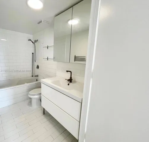 a bathroom with a bathtub shower sink mirror and toilet