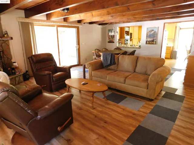 a living room with furniture and a dining table with wooden floor