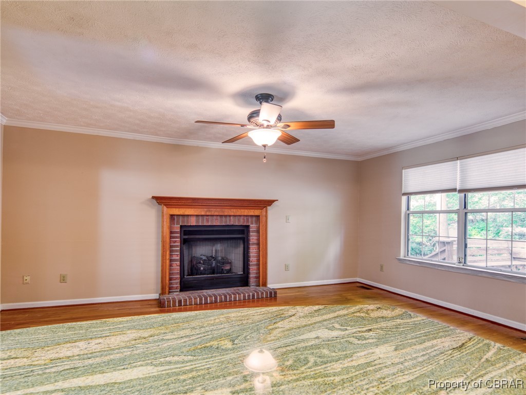 6 Ruth Circle Hampton, VA 23666 - Photo 10 of 50 Unfurnished living room with a textured ceiling, hardwood / wood-style floors, ceiling fan, crown molding, and a fireplace