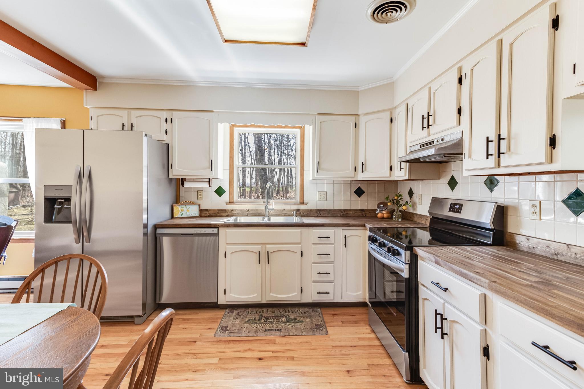 1966 Vandyke Greenspring Road Smyrna, DE 19977 - Photo 10 of 45 a kitchen with stainless steel appliances granite countertop a stove a sink dishwasher a refrigerator white cabinets and wooden floor next to a window