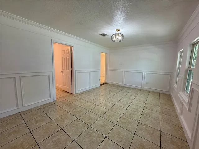 an empty room with chandelier fan and windows