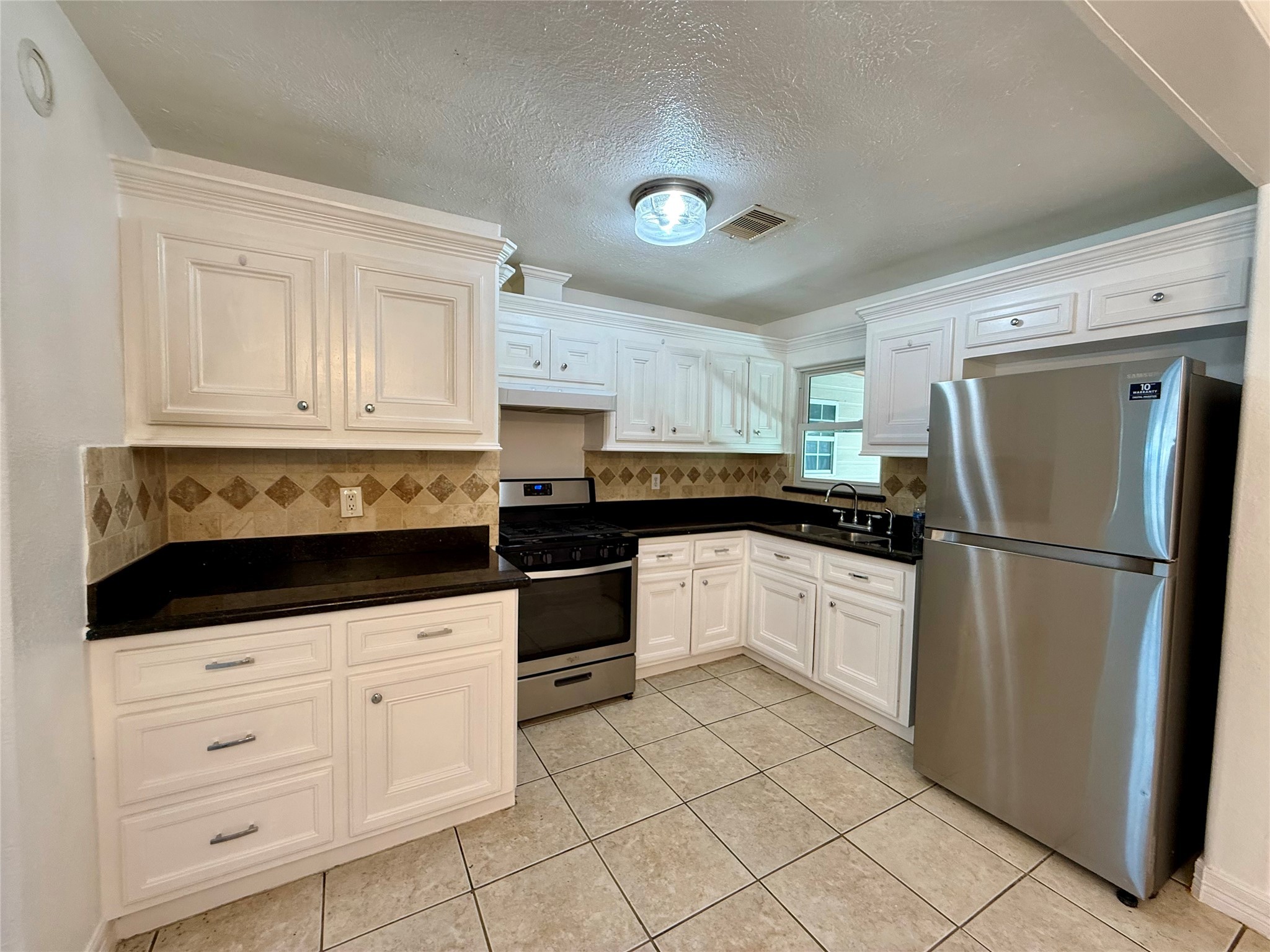5701 Luna Street Houston, TX 77076 - Photo 22 of 50 a kitchen with granite countertop white cabinets and stainless steel appliances