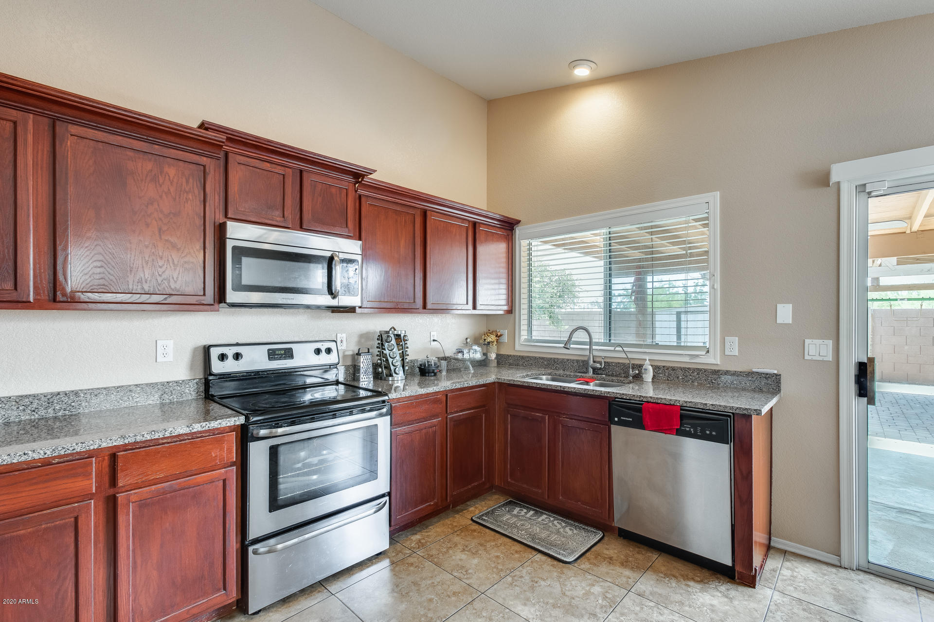 8713 West Coronado Road Phoenix, AZ 85037 - Photo 11 of 27 a kitchen with stainless steel appliances granite countertop a sink stove and microwave