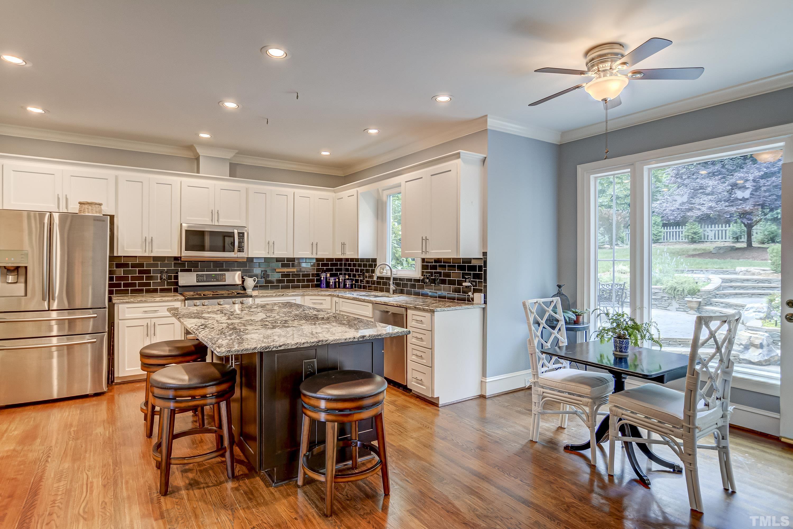 1309 Wescott Drive Raleigh, NC 27614 - Photo 10 of 32 a kitchen with stainless steel appliances granite countertop a stove a refrigerator a kitchen island a dining table and chairs with wooden floor