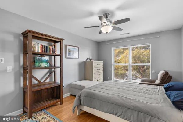 a bedroom with a bed a dresser and a large window