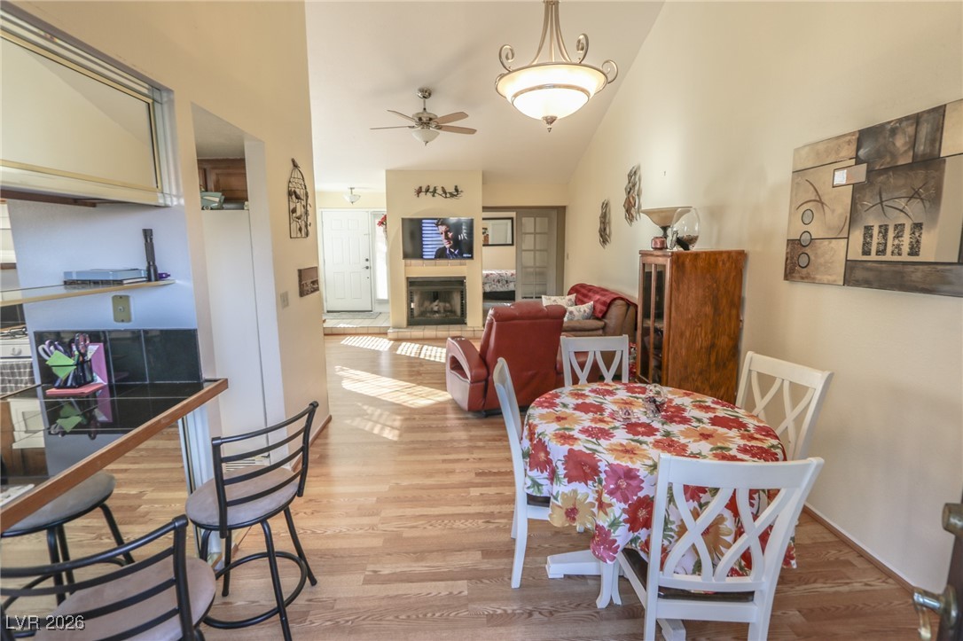 3201 La Mancha Way Henderson, NV 89014 - Photo 14 of 43 Dining area with vaulted ceiling, light wood-type flooring, a ceiling fan, and a fireplace with raised hearth