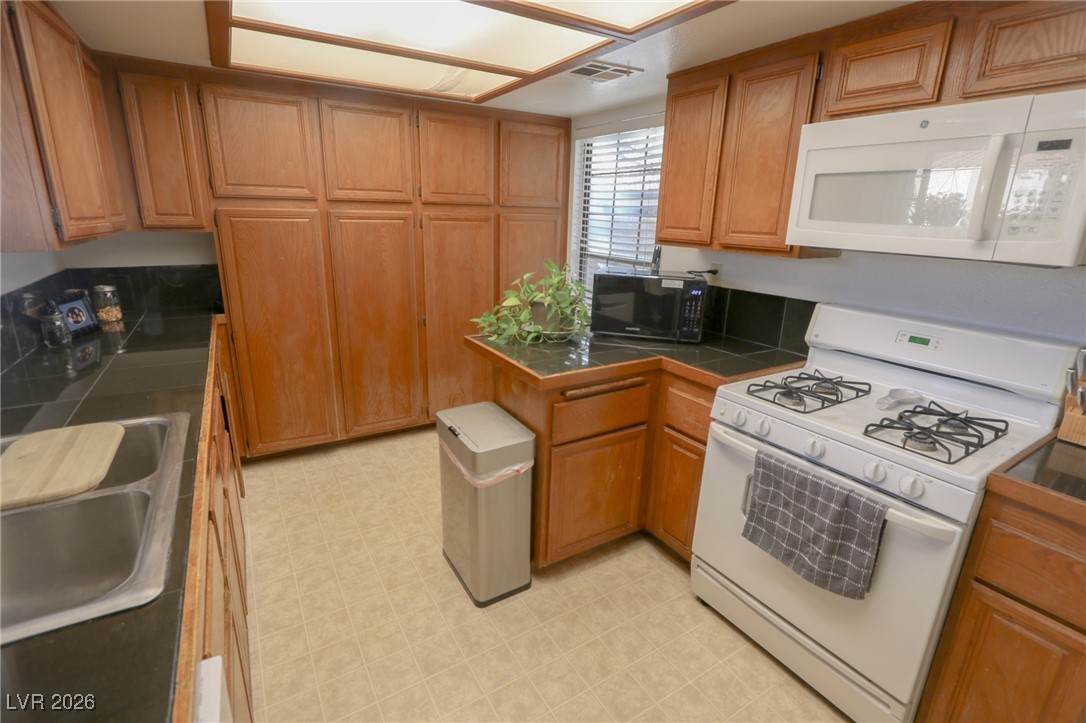 3201 La Mancha Way Henderson, NV 89014 - Photo 6 of 43 Kitchen with white appliances, light floors, and brown cabinets