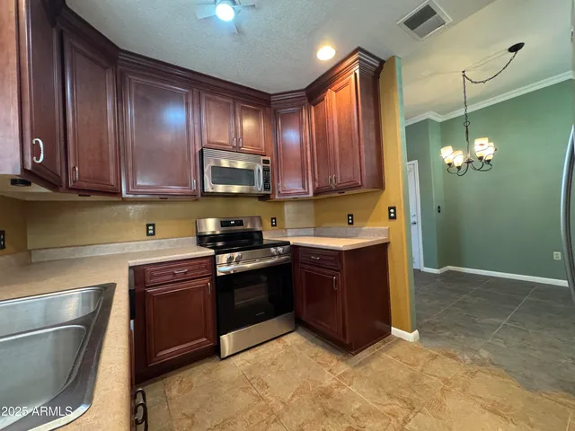 a kitchen with stainless steel appliances granite countertop a stove a sink dishwasher and a refrigerator with wooden cabinets