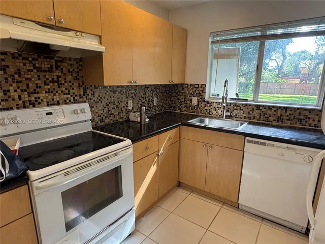 a kitchen with granite countertop a sink a stove and cabinets