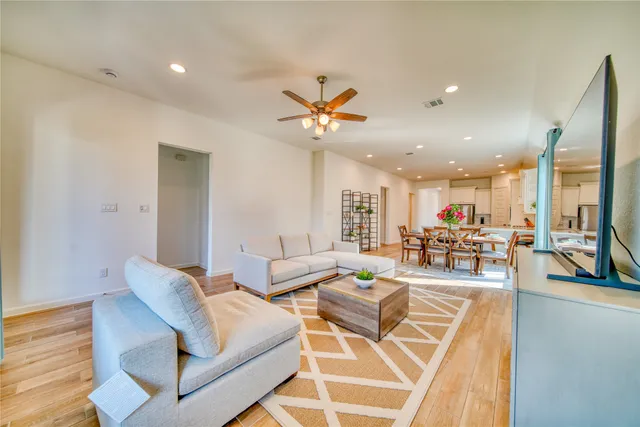 a living room with furniture kitchen view and a chandelier