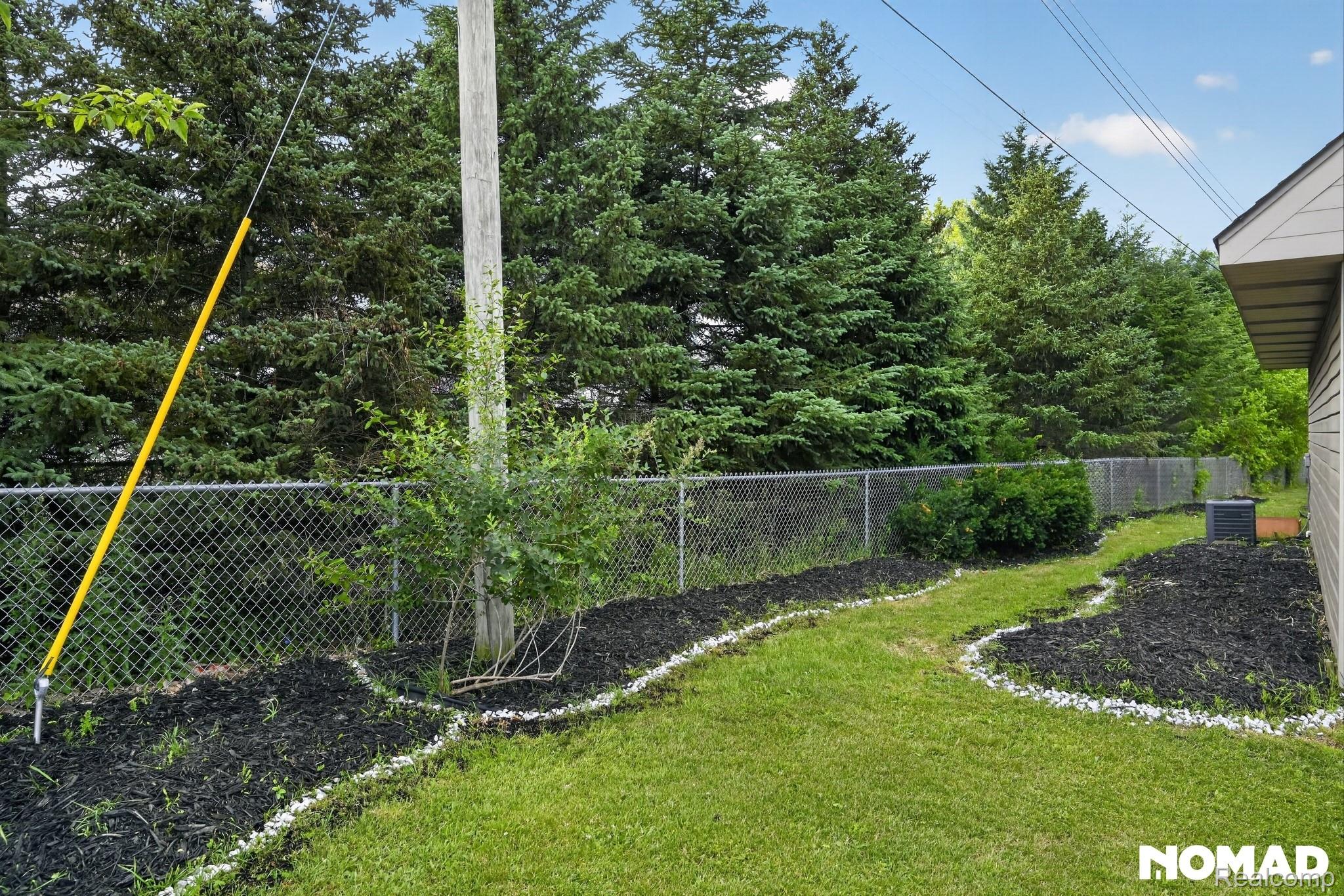 8315 Hilton Road Brighton, MI 48114 - Photo 7 of 26 Expansive green lawn featuring distinct mulched garden beds lined with white stone