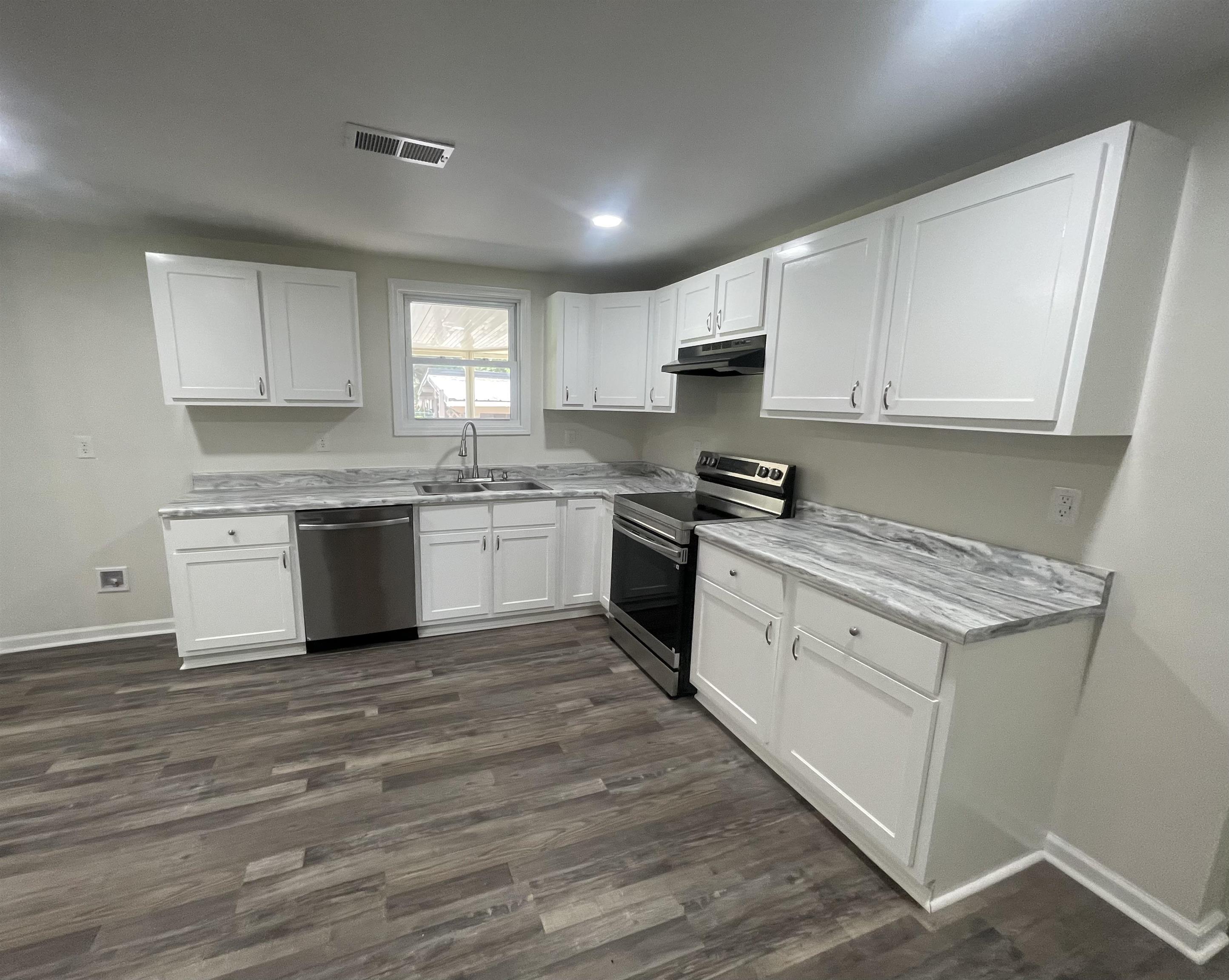 815 Fawn Road Oakland, TN 38060 - Photo 12 of 29 Kitchen featuring stainless steel appliances, a sink, under cabinet range hood, white cabinetry, and baseboards