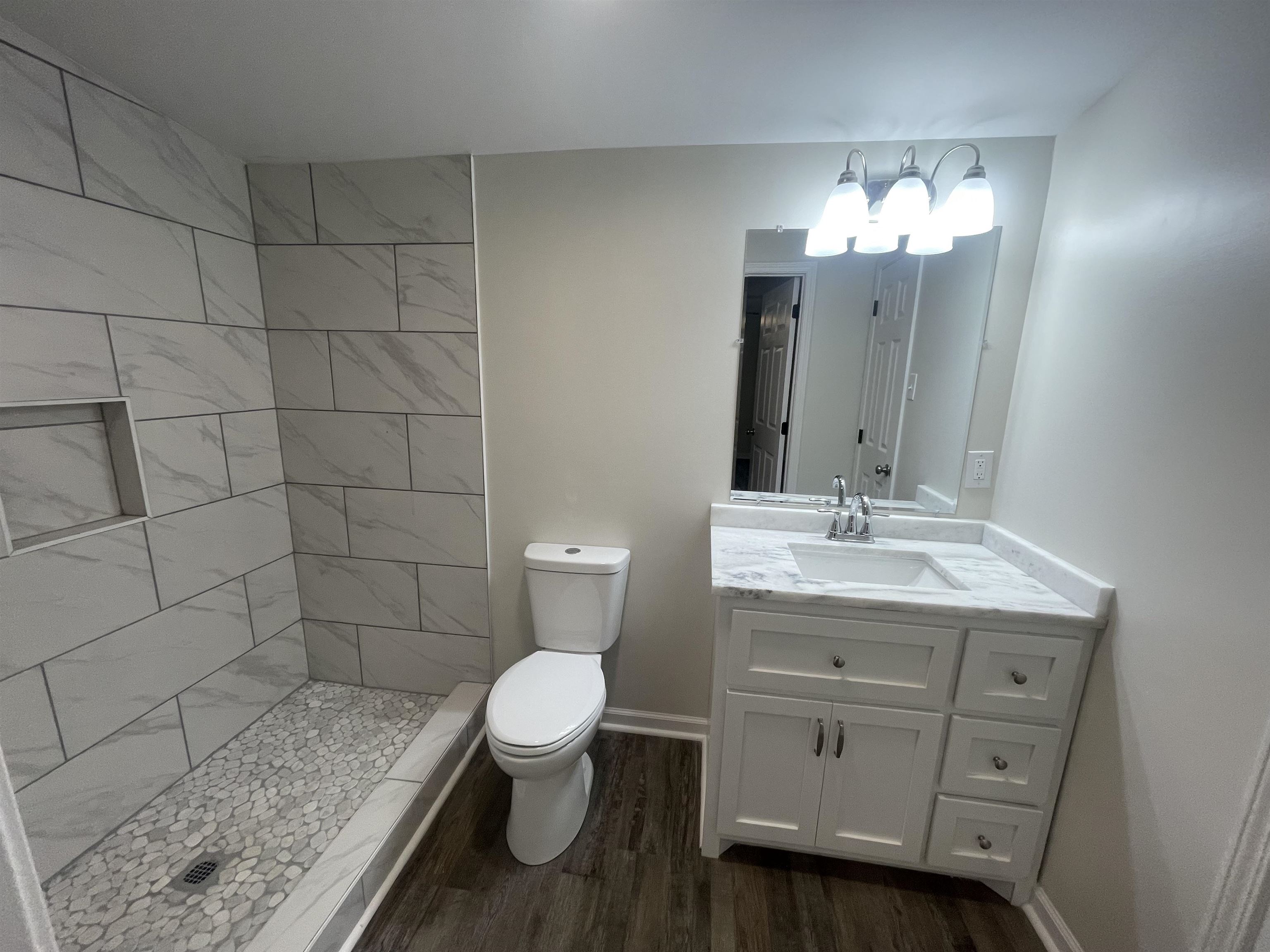 815 Fawn Road Oakland, TN 38060 - Photo 18 of 29 Bathroom with vanity, toilet, wood finished floors, a tile shower, and baseboards