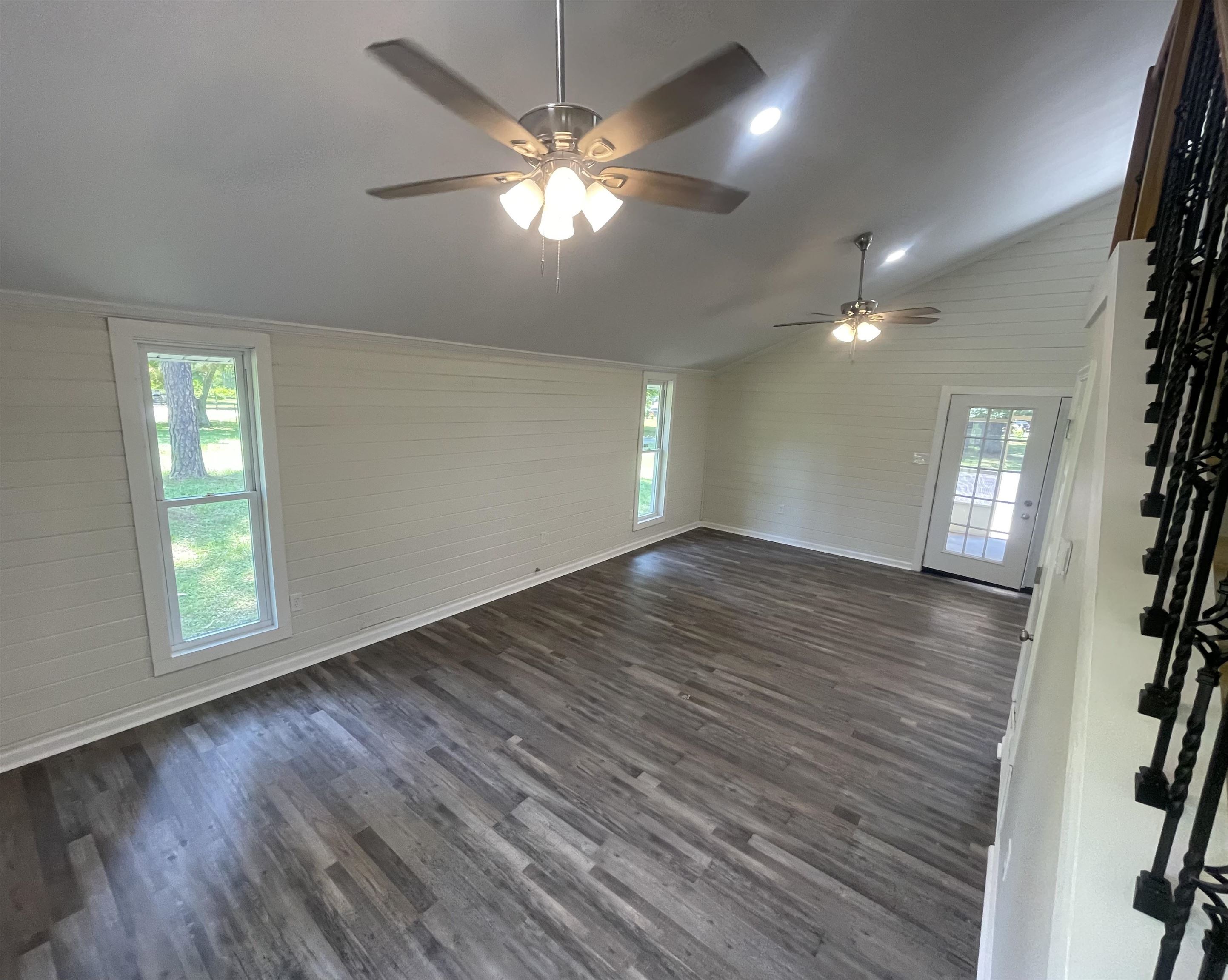 815 Fawn Road Oakland, TN 38060 - Photo 7 of 29 Unfurnished living room with ceiling fan, vaulted ceiling, dark wood-style flooring, baseboards, and wood walls