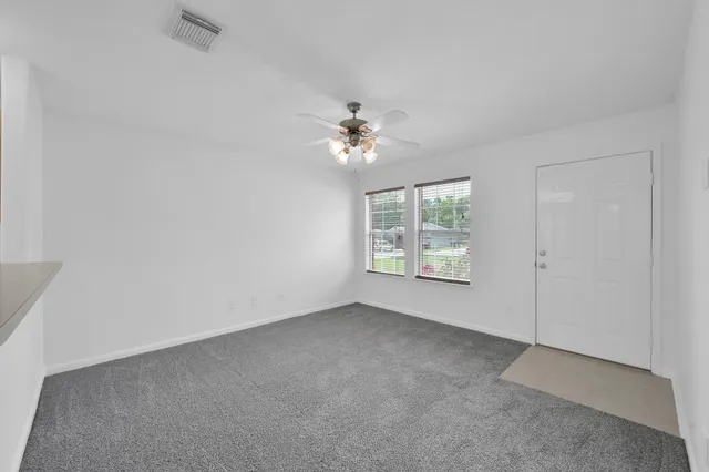 an empty room with windows and fan