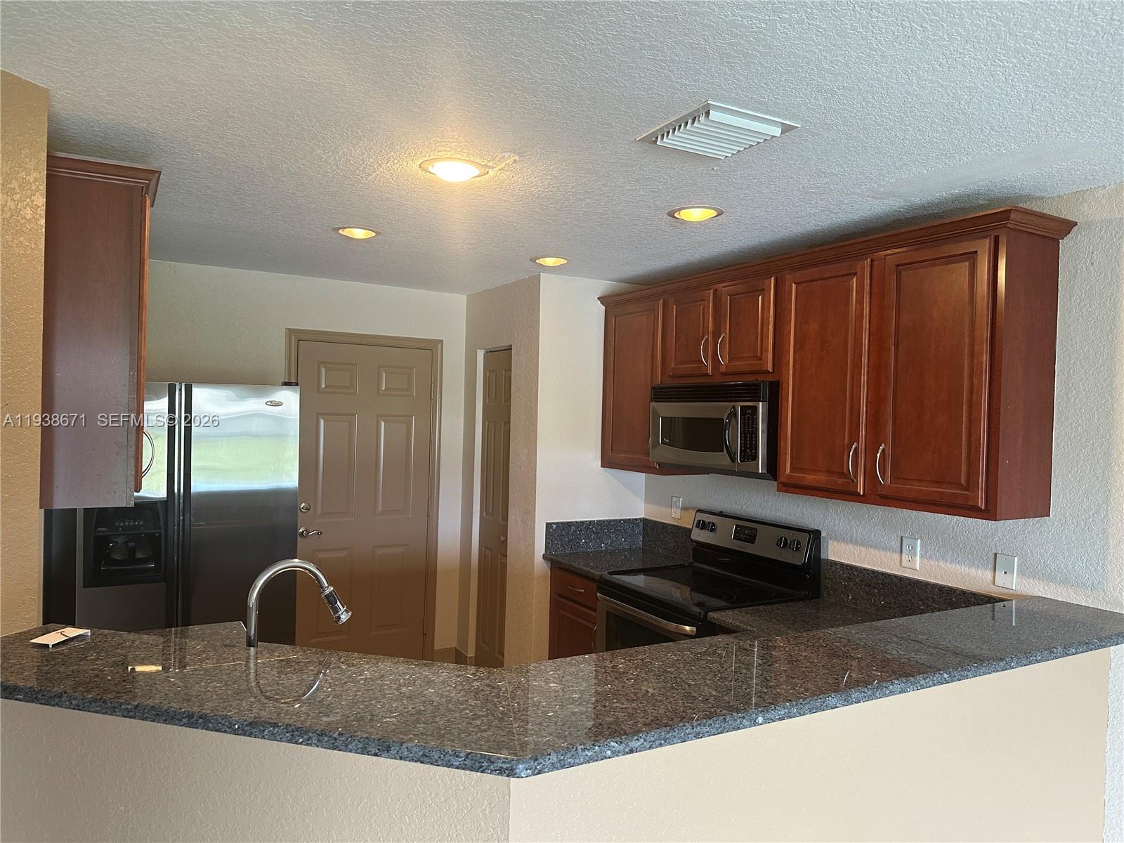 5954 Royal Way Tamarac, FL 33321 - Photo 12 of 28 a kitchen with granite countertop a stove a microwave a sink and a counter top space