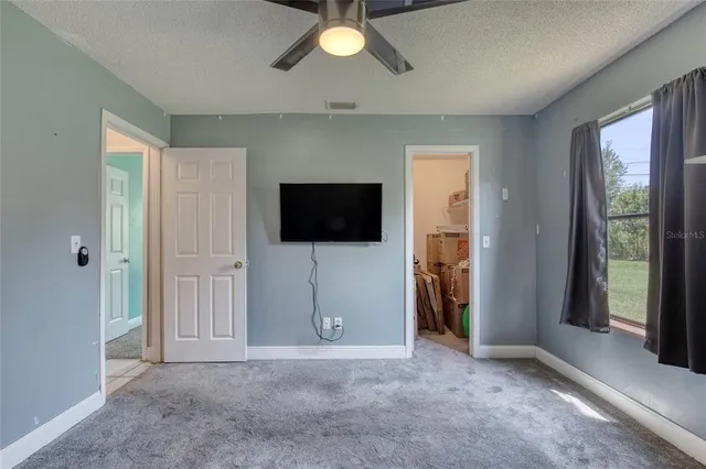 a living room with a flat screen tv and a ceiling fan