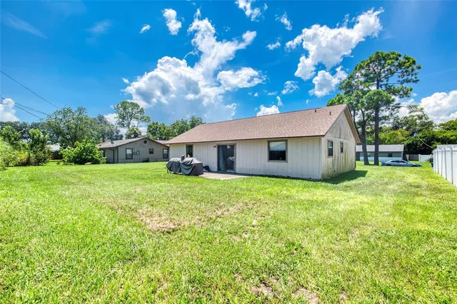 a backyard of a house with table and chairs plants and large tree