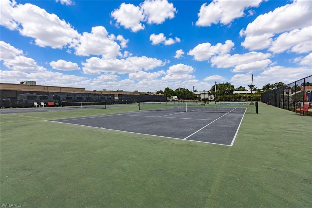 600 Neapolitan Way, Unit 449 Naples, FL 34103 - Photo 28 of 44 Tennis court facility featuring multiple courts with dark playing surfaces and green surrounds