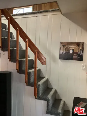 a view of a white house with a large tree and wooden fence
