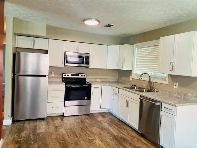 a kitchen with granite countertop a refrigerator stove and sink