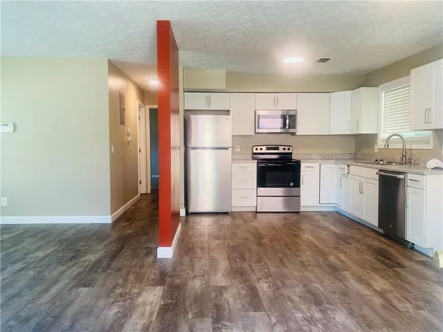 a kitchen with stainless steel appliances granite countertop a refrigerator a stove top oven and sink