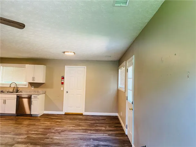 a view of a kitchen with a sink and dishwasher a refrigerator with wooden floor