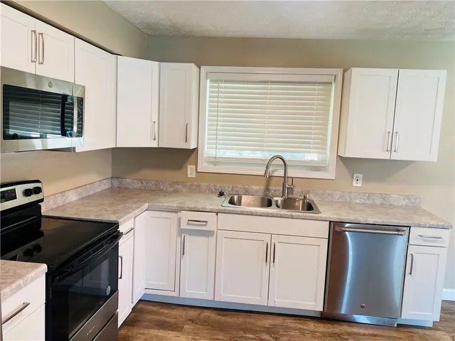 a kitchen with white cabinets and appliances
