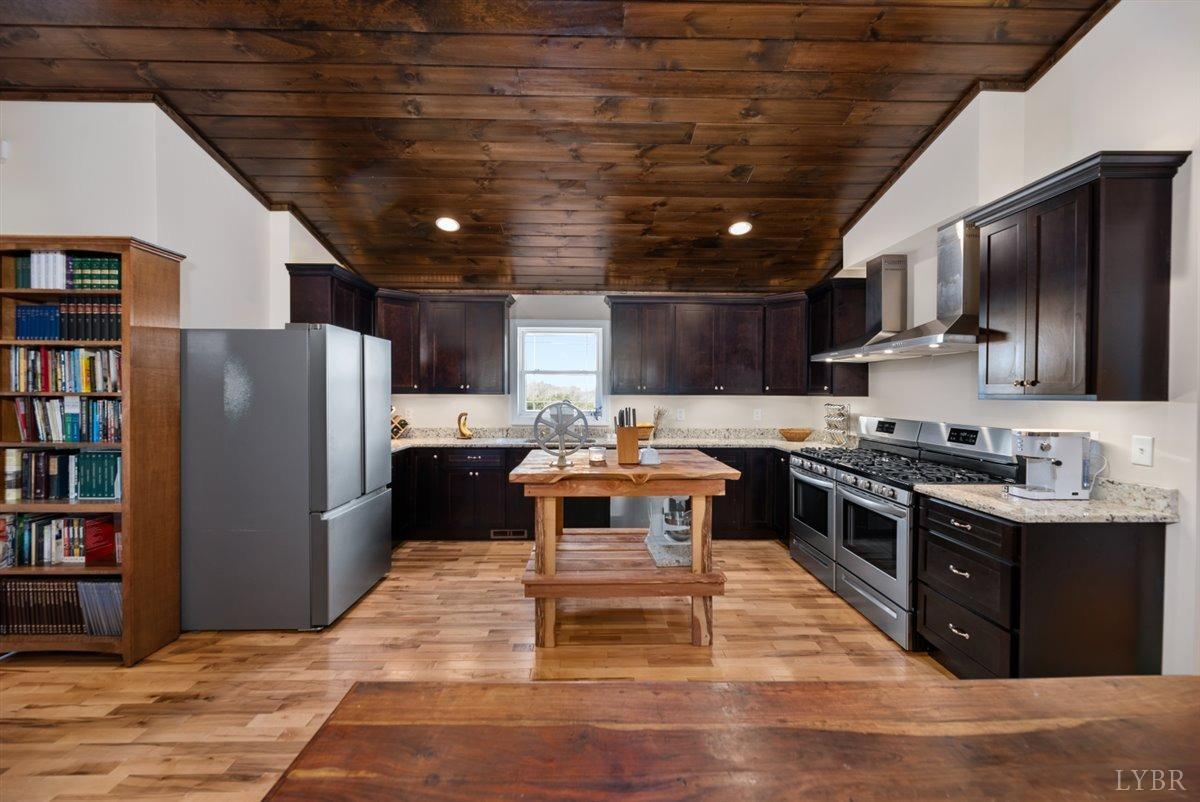 4625 Lowry Road Goode, VA 24556 - Photo 8 of 56 a kitchen with stainless steel appliances kitchen island granite countertop a table chairs and a refrigerator