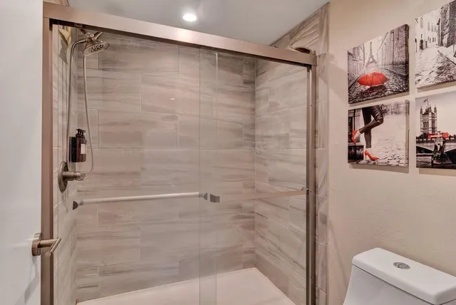 a bathroom with a shower and a toilet next to other door