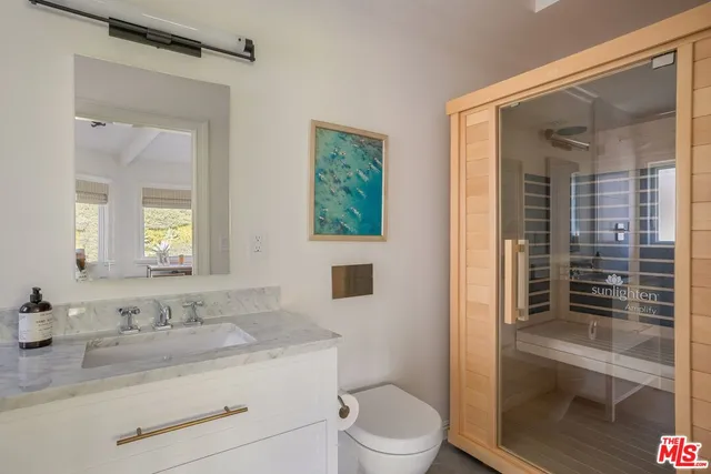 a bathroom with a granite countertop sink a mirror a toilet and shower