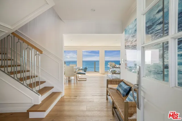 a living room with furniture large windows and wooden floor