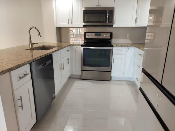 a kitchen with stainless steel appliances granite countertop a stove a sink and a microwave