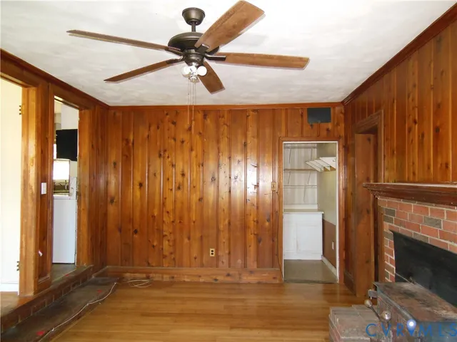 a view of empty room with wooden floor and fan