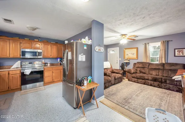 a large open kitchen with stainless steel appliances kitchen island granite countertop a refrigerator a stove a sink a dining table and chairs with wooden floor